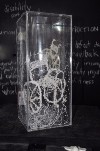 Photography of artwork from A Thousand Threads collection. Image description includes threads shaped into a wheelchair incased in a glass vase.  A Thousand Threads copyright Elaine Steward, 2016